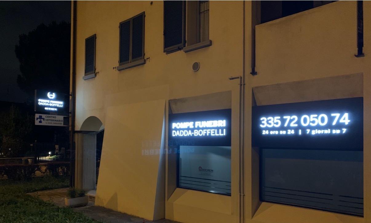 Facciata crema di notte con vetrine luminose Pompe Funebri Dadda-Boffelli e numero 335 72 050 74, 24 ore su 24